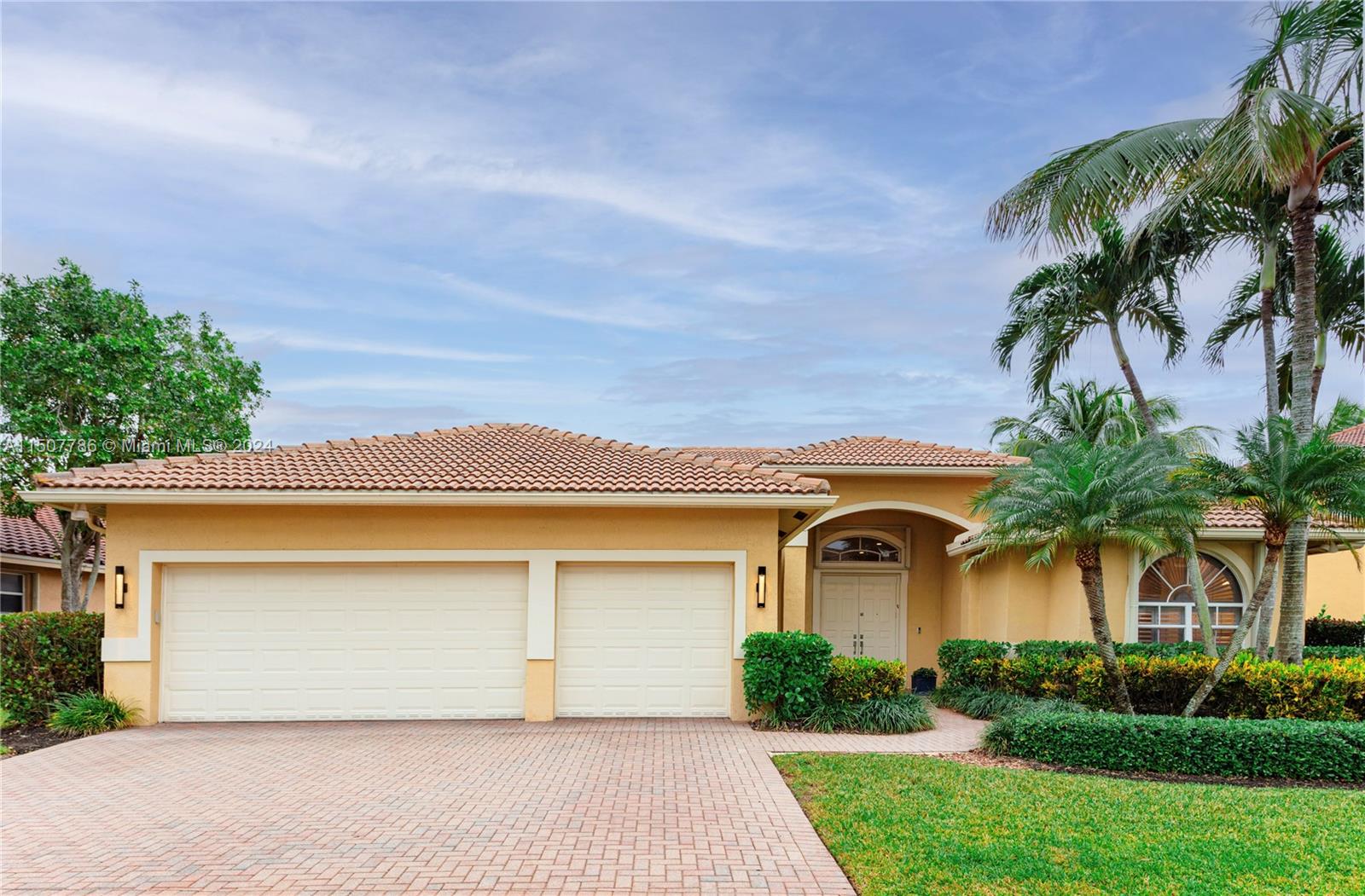 front view of a house with a yard and palm trees