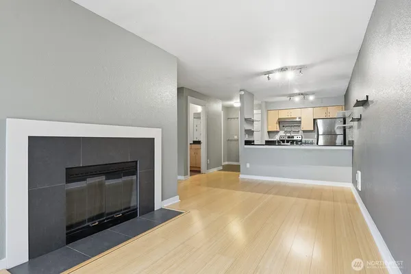 a large white kitchen with a fireplace and wooden floor