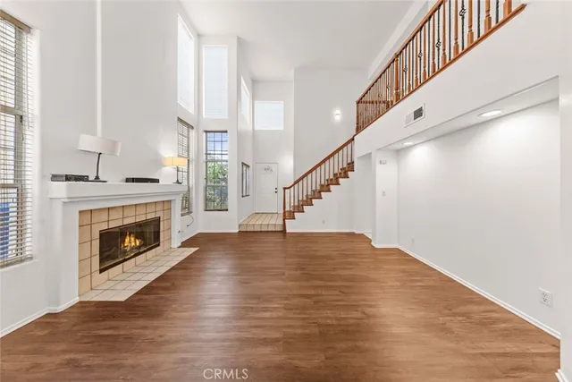 a view of an empty room with wooden floor fireplace and windows