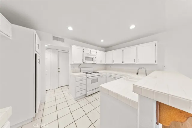 a kitchen with white cabinets and white appliances