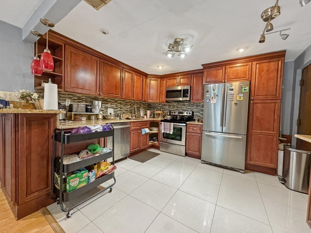 305 Riverside Avenue, Unit 24 Medford, MA 02155 - Photo 5 of 11 a kitchen with stainless steel appliances granite countertop a refrigerator and a stove top oven