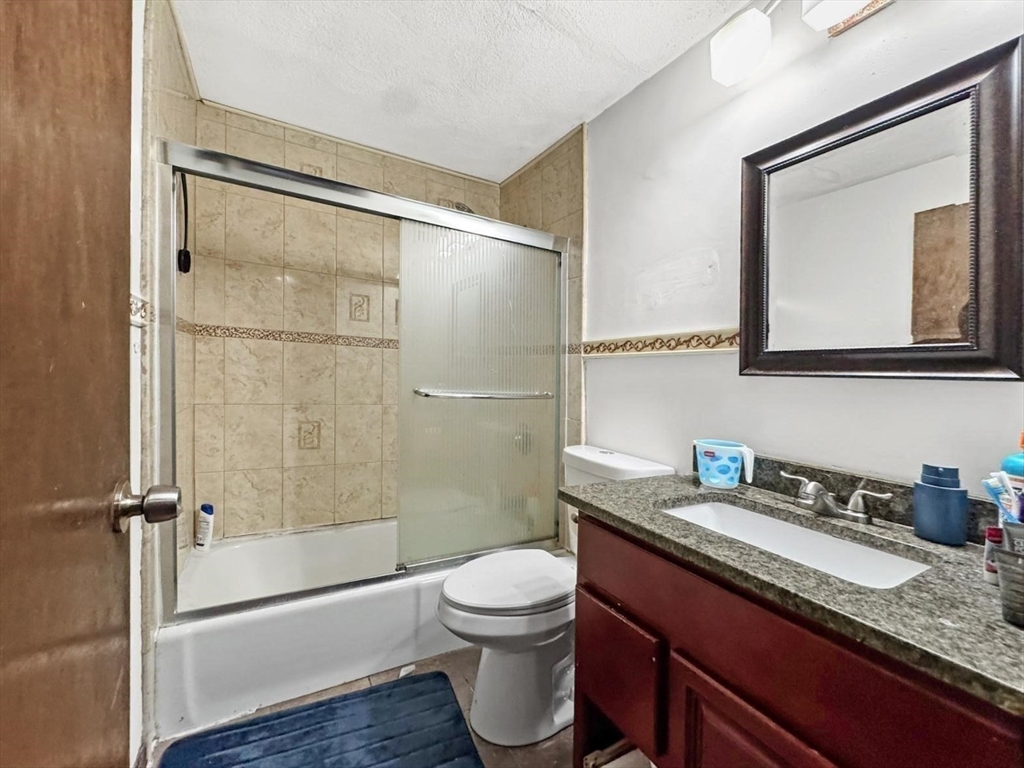305 Riverside Avenue, Unit 24 Medford, MA 02155 - Photo 9 of 11 a bathroom with a granite countertop sink toilet and shower