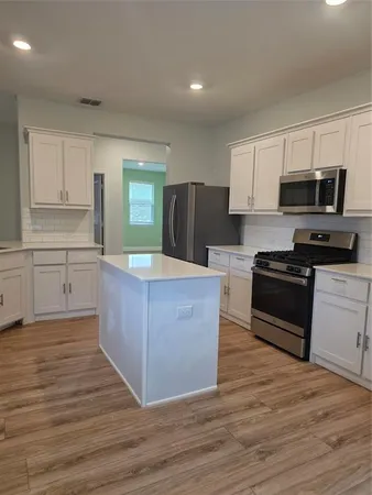 a kitchen with stainless steel appliances kitchen island granite countertop a stove a sink and a refrigerator