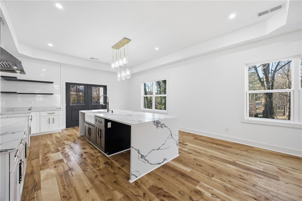 6465 Yacht Club Road Flowery Branch, GA 30542 - Photo 18 of 45 a large white kitchen with wooden floor and a window