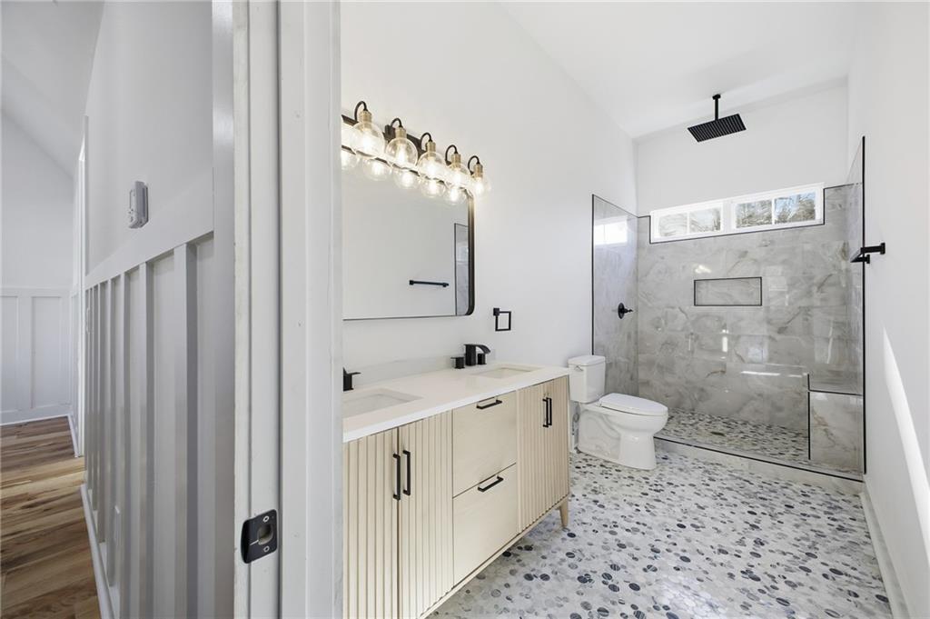 6465 Yacht Club Road Flowery Branch, GA 30542 - Photo 35 of 45 a spacious bathroom with a double vanity sink a toilet and a mirror