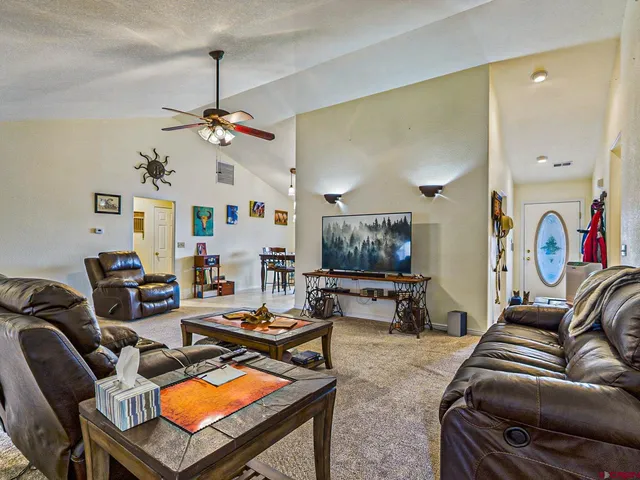 a living room with furniture a flat screen tv and kitchen view