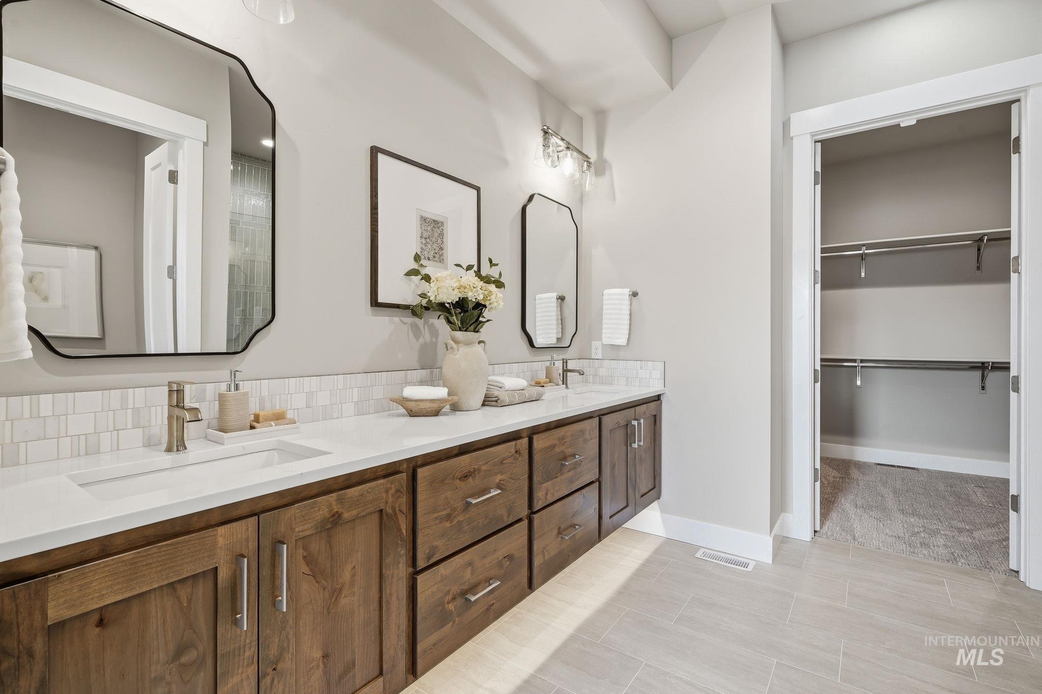 470 South Radiator Way Boise, ID 83716 - Photo 45 of 50 Spacious bathroom vanity featuring dual sinks, wood-finish cabinetry, and white countertops with a mosaic tile backsplash