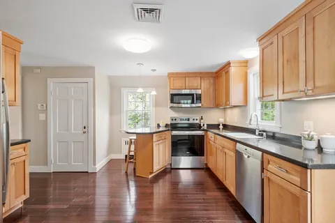 a kitchen with stainless steel appliances granite countertop a refrigerator a sink dishwasher a stove and white countertops with wooden floor
