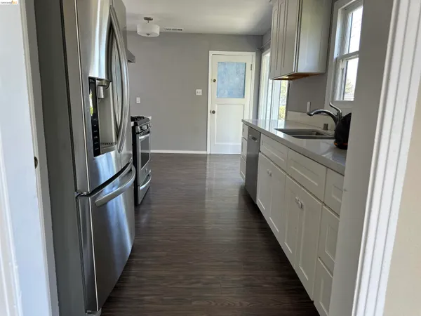 a kitchen with stainless steel appliances a refrigerator and wooden floor