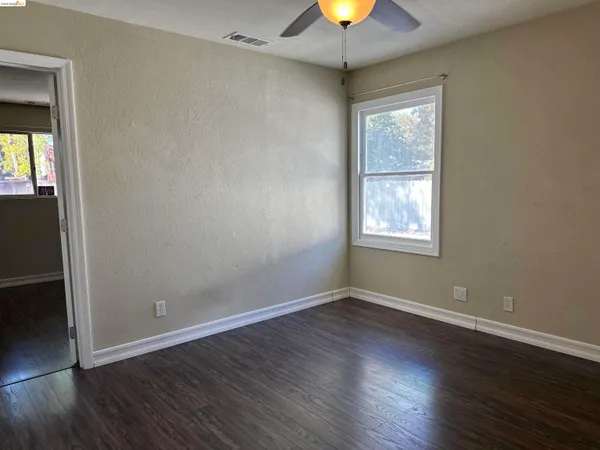 an empty room with wooden floor chandelier and windows