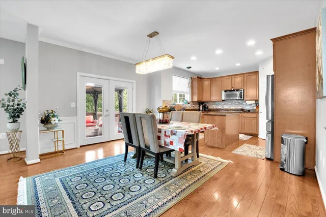 a living room with dining table a rug kitchen view and a potted plant