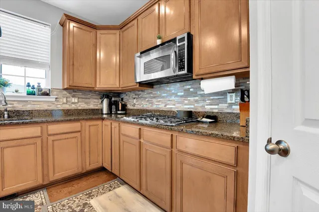 a kitchen with granite countertop a sink a stove and cabinets