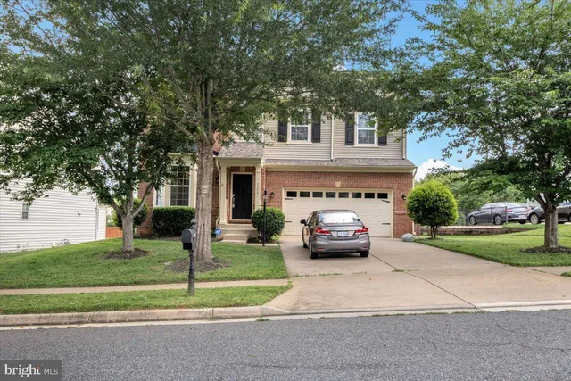 a front view of a house with a garden and trees