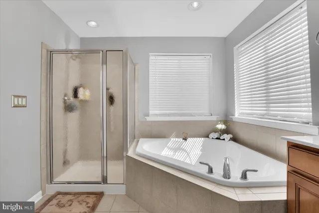 a bathroom with a tub a window and a glass door shower