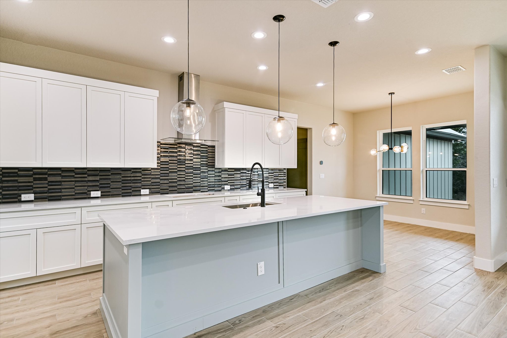 31 Peace Pipe Wimberley, TX 78676 - Photo 5 of 20 Kitchen featuring light stone counters, light wood-type flooring, white cabinetry, and decorative backsplash