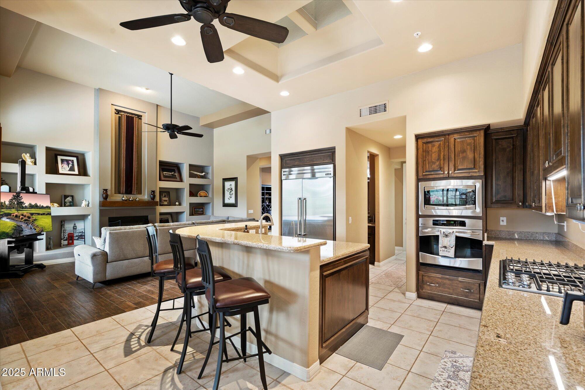 6867 East Crimson Sky Trail Scottsdale, AZ 85266 - Photo 20 of 97 a kitchen with stainless steel appliances kitchen island granite countertop a table chairs and a refrigerator