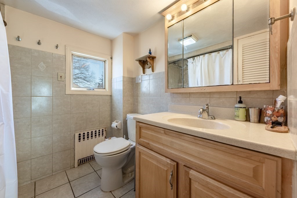 28 Ellsworth Street Medford, MA 02155 - Photo 16 of 23 a bathroom with a granite countertop sink a toilet and a mirror