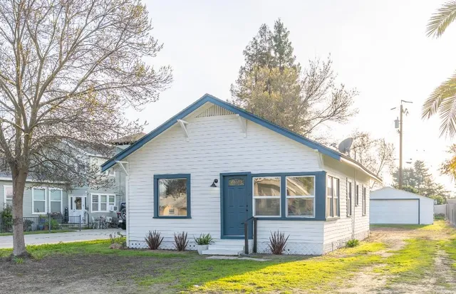 a view of a house with a big yard and large tree