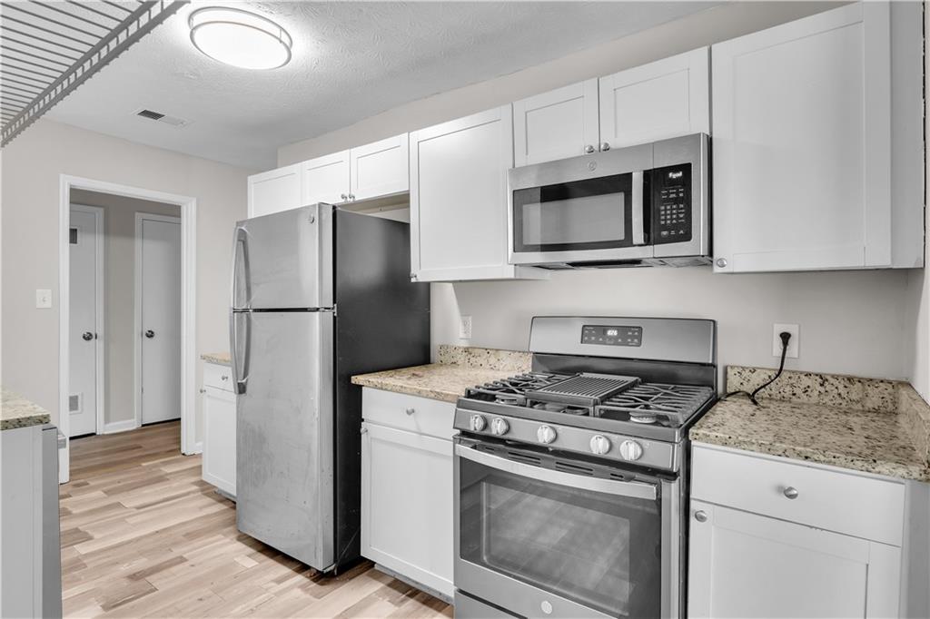 5796 Bobbin Lane Lithonia, GA 30058 - Photo 6 of 17 a kitchen with stainless steel appliances white cabinets and a stove top oven