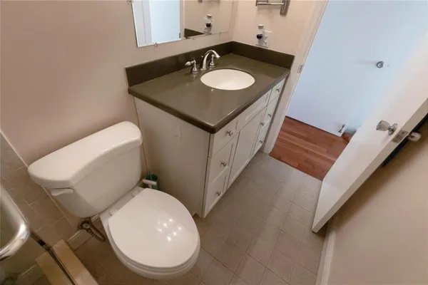 a bathroom with a granite countertop toilet sink and mirror