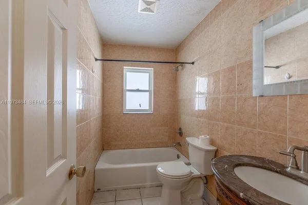 a bathroom with a granite countertop toilet sink and mirror