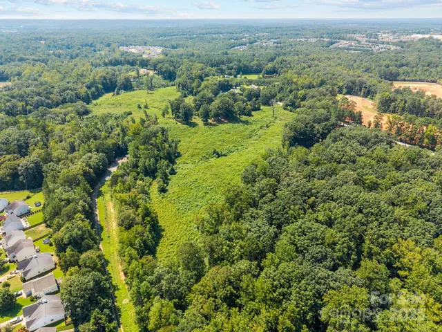 an aerial view of residential house with outdoor space and trees all around