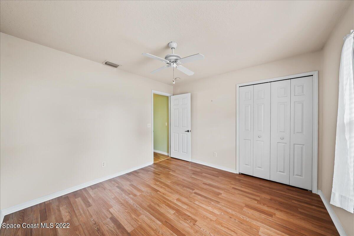 1965 Sundew Court Northeast Palm Bay, FL 32905 - Photo 13 of 29 a view of a room with wooden floor and a ceiling fan