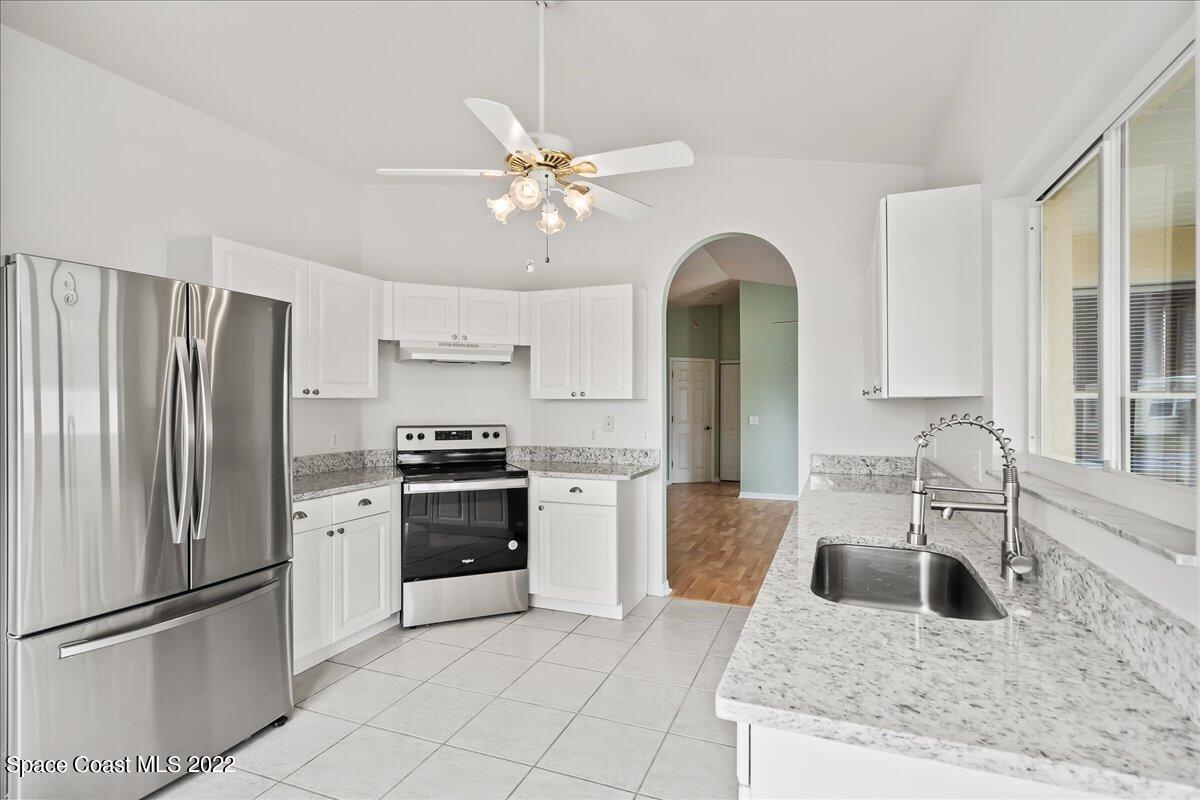 1965 Sundew Court Northeast Palm Bay, FL 32905 - Photo 7 of 29 a kitchen with stainless steel appliances granite countertop a refrigerator a stove a sink and white cabinets