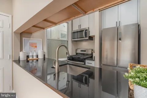 a kitchen with stainless steel appliances granite countertop a refrigerator a stove and a sink with wooden floor