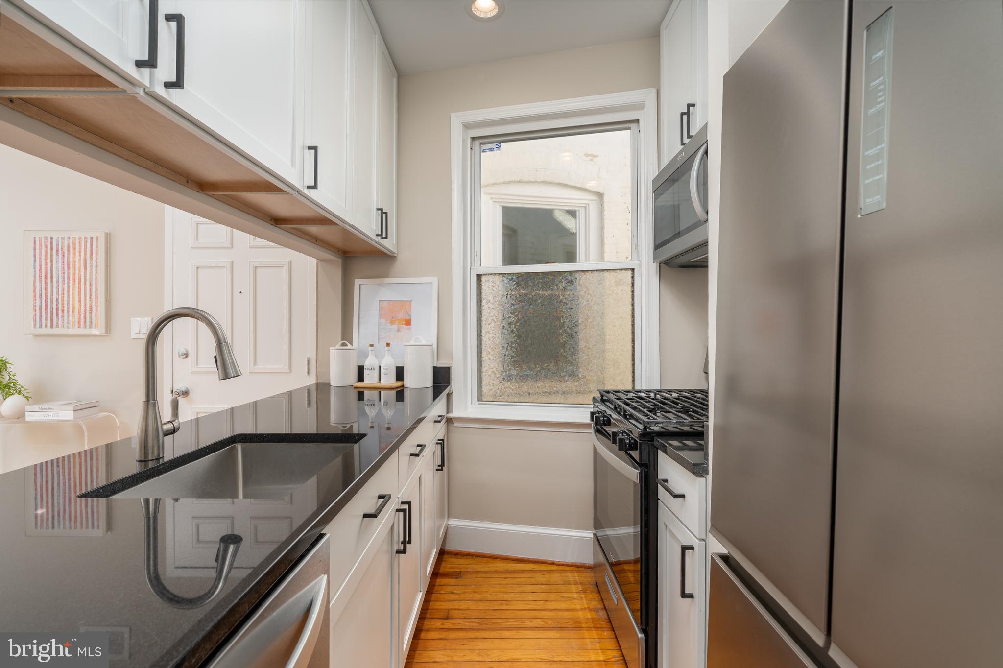 1218 D Street Southeast, Unit 4 Washington, DC 20003 - Photo 14 of 30 a kitchen with a refrigerator sink and white cabinets