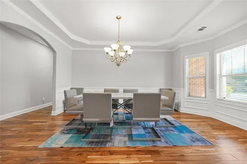 a dining room with wooden floor a potted plant and windows