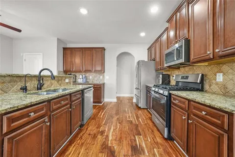 a large kitchen with stainless steel appliances granite countertop a lot of counter space and wooden floor