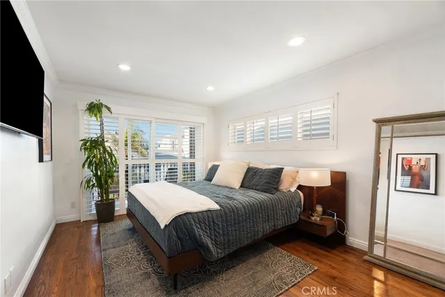 a bedroom with a bed a flat screen tv and a potted plant
