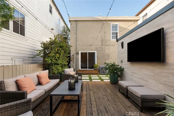 a view of a patio with couches table and chairs with wooden floor and fence