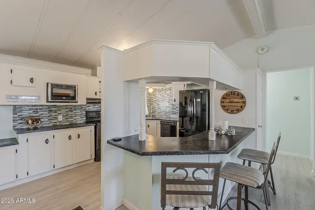 a kitchen with granite countertop stainless steel appliances a table chairs and a refrigerator