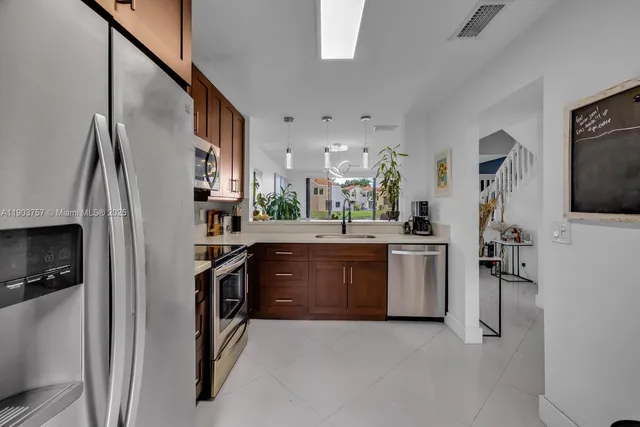 a kitchen with stainless steel appliances granite countertop a refrigerator a stove and a sink