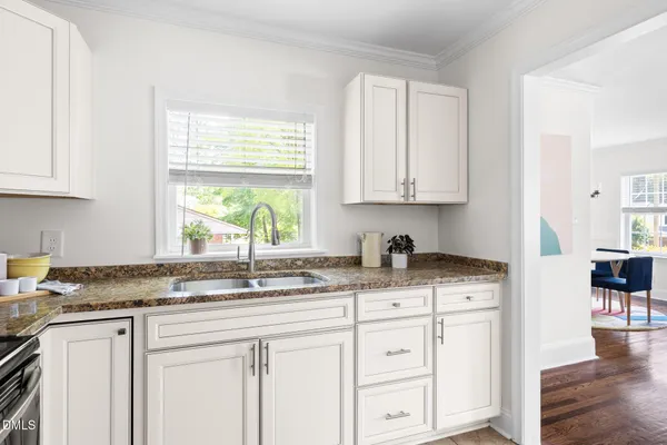 a kitchen with granite countertop white cabinets and a window