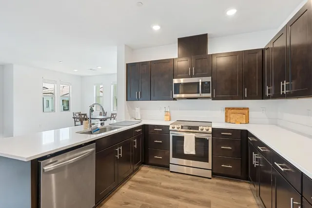 a kitchen with stainless steel appliances wooden cabinets a sink and a refrigerator