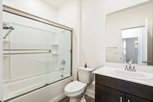 a kitchen with stainless steel appliances kitchen island granite countertop a refrigerator a stove a dining table and chairs with wooden floor