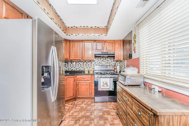 a kitchen with stainless steel appliances granite countertop a stove a sink and a refrigerator