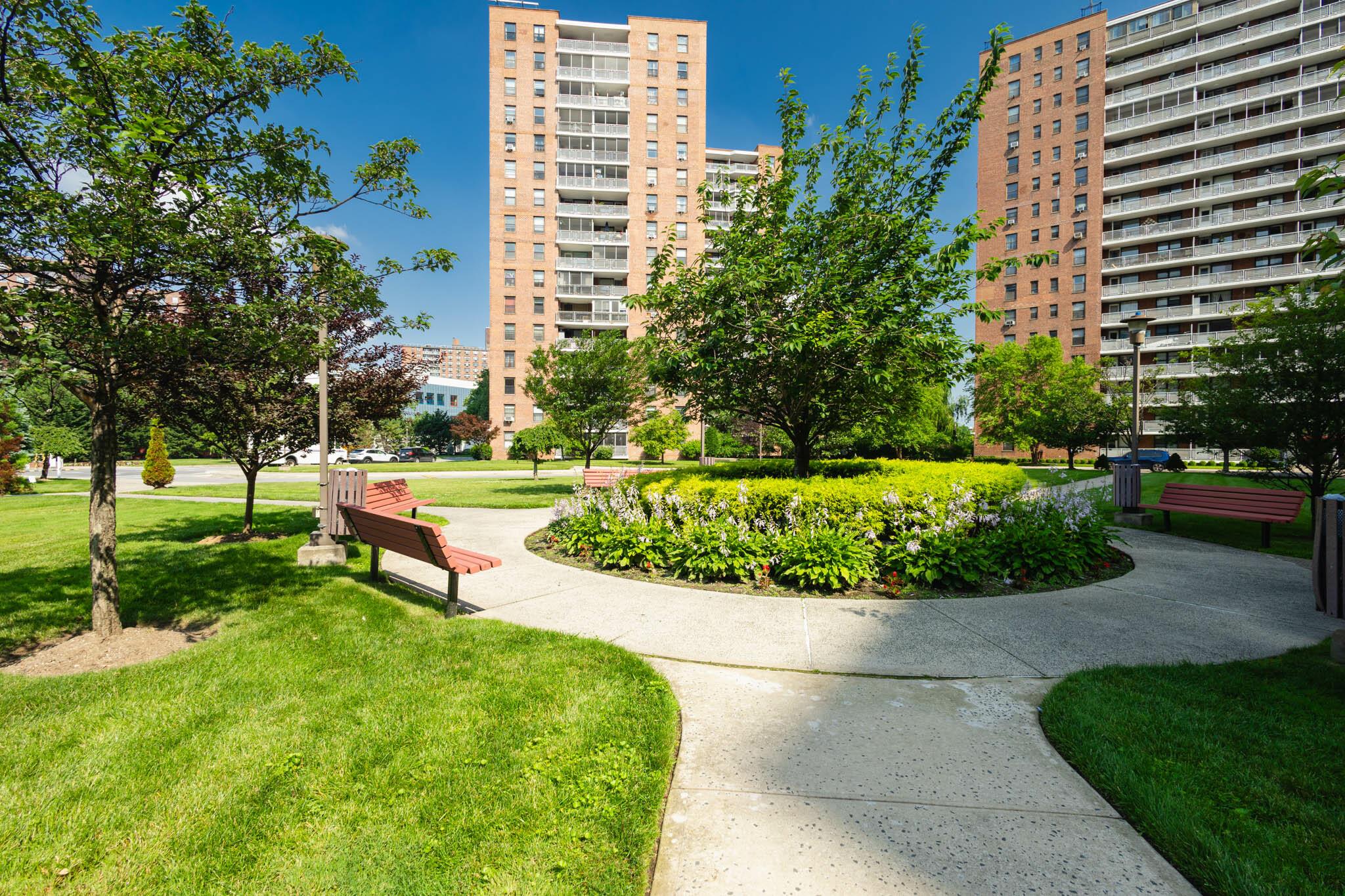61-25 98th Street, Unit 11E Queens, NY 11374 - Photo 27 of 31 a garden with a bench and trees in the background