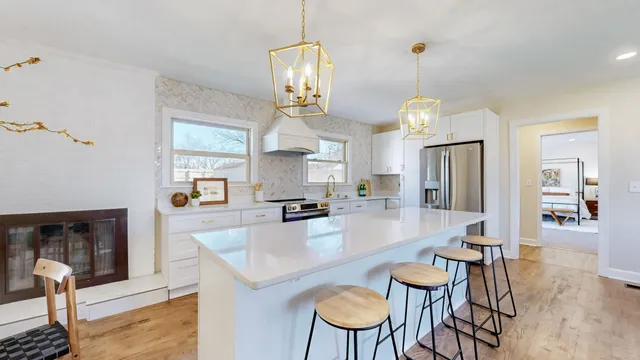 a dining room with wooden floor a chandelier a wooden table and chairs