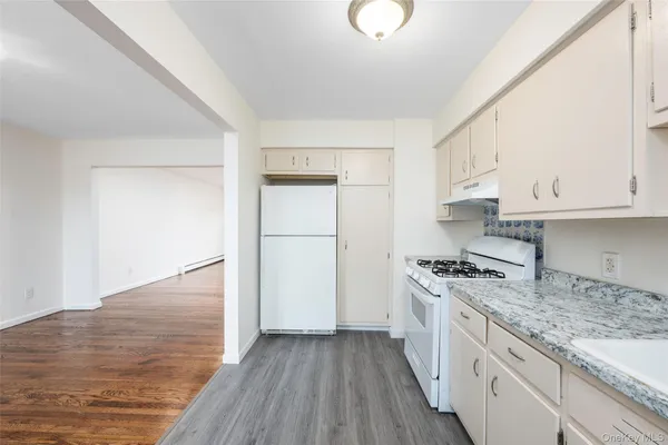 a kitchen with granite countertop white cabinets and white appliances