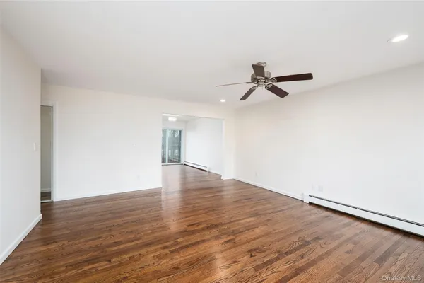 a view of a room with wooden floor and a ceiling fan