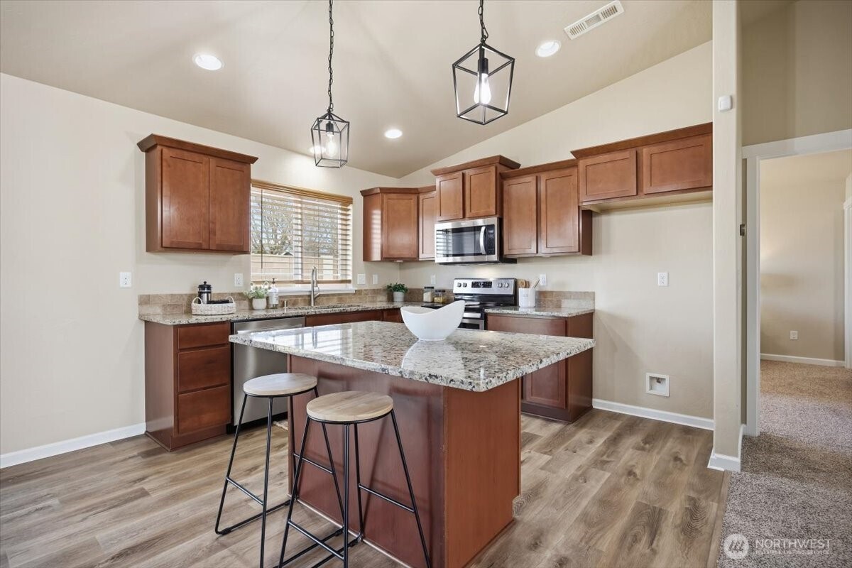 3709 Morehouse Place Pasco, WA 99301 - Photo 15 of 32 a kitchen with kitchen island granite countertop a sink refrigerator and microwave