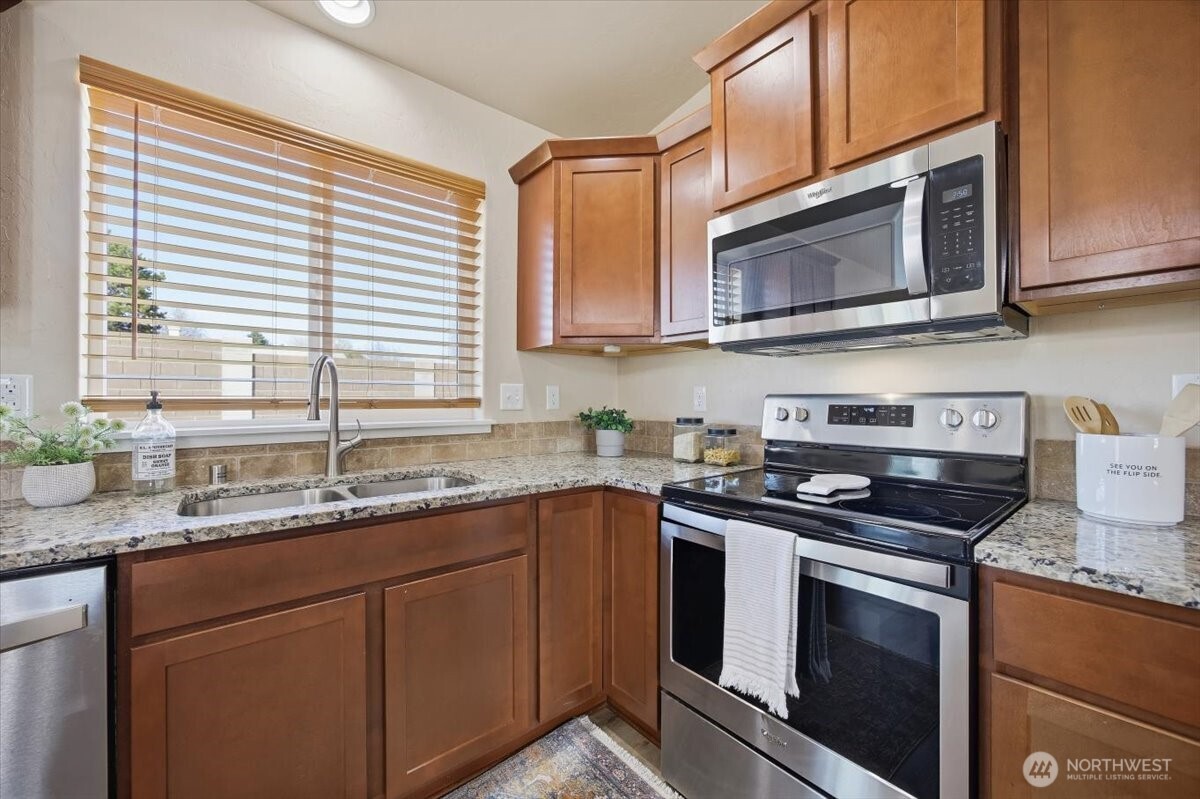 3709 Morehouse Place Pasco, WA 99301 - Photo 17 of 32 a kitchen with stainless steel appliances granite countertop a sink a stove and microwave with wooden cabinets