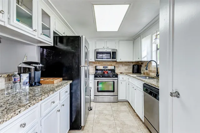 a kitchen with stainless steel appliances granite countertop a refrigerator and a stove top oven