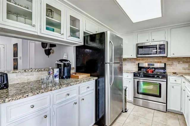 a kitchen with stainless steel appliances granite countertop a refrigerator and a stove top oven