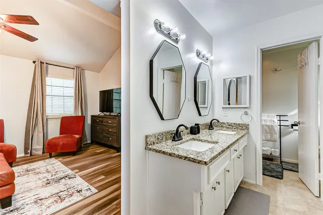 a en suite bathroom with a granite countertop sink and a mirror
