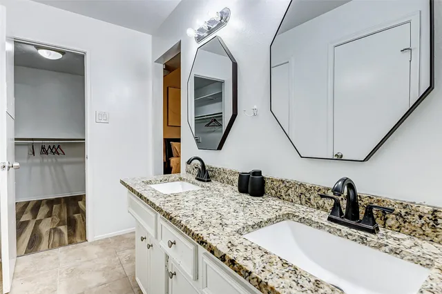 a bathroom with a granite countertop double vanity sink and a mirror